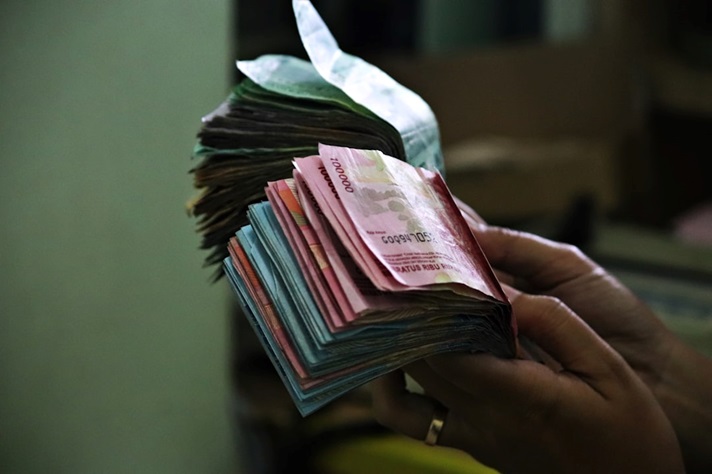 Close-up of hands holding wads of cash.